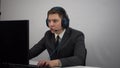 A businessman plays an online computer game while sitting in the office. A young man in a suit and headphones plays with Royalty Free Stock Photo