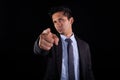 Businessman pointing forward with his finger. Young adult with serious and distrustful expression judging with finger
