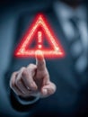 Businessman pointing at a glowing red warning symbol representing caution and alert in digital technology and cybersecurity Royalty Free Stock Photo