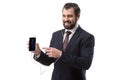cheerful bearded businessman listening music with earphones and pointing at smartphone