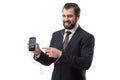 Cheerful bearded businessman listening music with earphones and pointing at smartphone with tumblr website