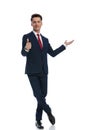 businessman pointing to side, giving thumbs up with crossed feet