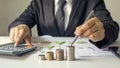 Businessman pointing to a stack of coins where plants are growing. Royalty Free Stock Photo