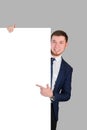 The businessman points with his index finger at the white blank board, standing on a gray background Royalty Free Stock Photo