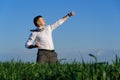 Businessman posing in a field, he goes in for sports and does strikes like martial arts or superman, green grass and blue sky as