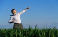 Businessman posing in a field, he goes in for sports and does strikes like martial arts or superman, green grass and blue sky as