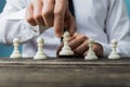 Businessman positioning white pawn chess piece in front of the others