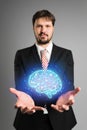 Businessman presenting an AI icon of a shining blue brain emitting energy and power