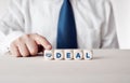 Businessman pressing his finger on the wooden cubes with the word deal. Business compromise or agreement Royalty Free Stock Photo