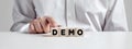 Businessman pressing his finger on the wooden cubes with the word demo. Demonstration test or trial Royalty Free Stock Photo