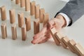 Businessman preventing wooden blocks toppling on a desk-business concept