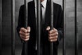 Businessman in prison hold bars