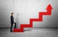 Businessman in profile walking up big red arrow in form of ladder Royalty Free Stock Photo