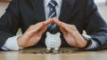 Businessman protect the piggybank in hand, donation, saving, charity, family finance plan concept, fundraising, superannuation,