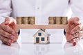 Businessman Protecting Stacked Coins On Seesaw Royalty Free Stock Photo