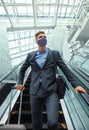 Businessman in protective mask at the airport going down the escalator