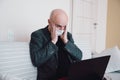 Businessman in protective mask sitting on the sofa he sees terrifying stock market results on the laptop.