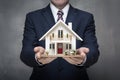 Businessman proudly displays house model, epitome of real estate success