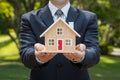 Businessman proudly displays house model, epitome of real estate success