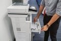 Businessman pull multi function office printer tray to put paper for printing documents