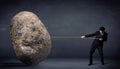 Businessman pulling huge rock with a rope