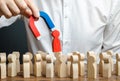 businessman pulls out a red figure of a man from the crowd with the help of a magnet. leader manages the business and forms a team