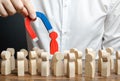 businessman pulls out a red figure of a man from the crowd with the help of a magnet. toxic, non-competent worker. Increase team