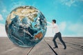 Businessman pushing Earth on wooden floor