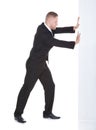 Businessman pushing the edge of a blank white sign Royalty Free Stock Photo