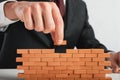 Businessman puts a brick to build a wall. Concept of new business, partnership, integration and startup.