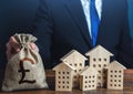 A businessman puts a british pound sterling money bag near the houses. Construction industry, rental business and hotel tourism.