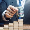 Businessman puts a dollars bundle on top of stairs. Business success, company profitability. Raising bids, increase interest rate