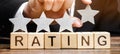 Businessman puts a fourth star above the word Rating on wooden blocks. The concept of the high rating of hotels and restaurants.