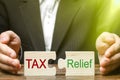 A businessman puts two puzzles with the words Tax and Relief. The concept of reducing the debt burden on business and local Royalty Free Stock Photo