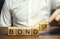 Businessman puts wooden blocks with the word Bonds. A bond is a security that indicates that the investor has provided a loan to Royalty Free Stock Photo