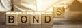 Businessman puts wooden blocks with the word Bonds. A bond is a security that indicates that the investor has provided a loan to Royalty Free Stock Photo