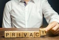 Businessman puts wooden blocks with the word Privacy. Keeping secret information about a personÃ¢â¬â¢s personality or activity and