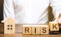 Businessman puts wooden blocks with the word Risk and a house. Real estate investment risk. Risky investments. Loss of property Royalty Free Stock Photo