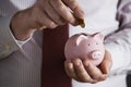 Businessman Putting Coin Into Piggy Bank