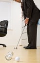 Businessman putting golf ball in office