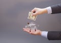 Businessman putting one dollar bill into glass piggy bank Royalty Free Stock Photo