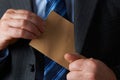 Businessman Putting Plain Brown Envelope In Jacket Pocket Royalty Free Stock Photo