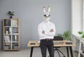 Businessman in rabbit head mask standing with folded hands in office Royalty Free Stock Photo