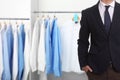 Businessman and rack with clean clothes at dry-cleaner`s. Space for text