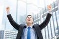 Businessman raising his fists in the air on blur office building