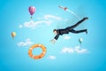 Businessman reaching to orange boat lifebuoy with hot air balloons and silver red space rocket in the air on blue Royalty Free Stock Photo