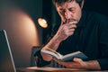 Businessman reading a book while sitting at office desk late at night Royalty Free Stock Photo