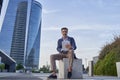 Businessman reading email received on a modern tablet while sitting outdoors in front of an office building, Caucasian Royalty Free Stock Photo