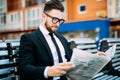 Handsome businessman reading a financial newspaper while sitting on bench outdoors Royalty Free Stock Photo