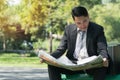 Businessman reading newspaper looking for new job in public park with copy space Royalty Free Stock Photo